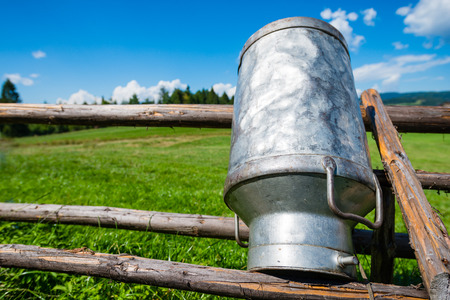 Old Milk Can Made of Aluminum. Old milk can made of metal to dry on a wooden stand - upside down - shallow depth of fieldの写真素材