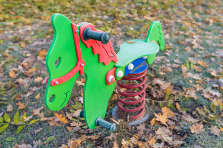 Empty colorful rocking spring horse at playground in autumn scenery - frozen - shallow depth of fieldの写真素材