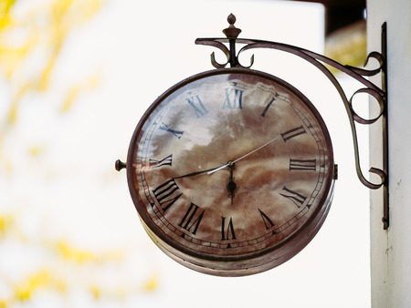 Big vintage old clock hanging on the wall with sky background