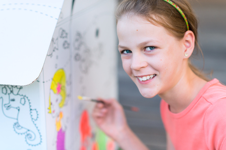Young Girl Painting Cardboard House In the Garden - shallow depth of fieldの写真素材