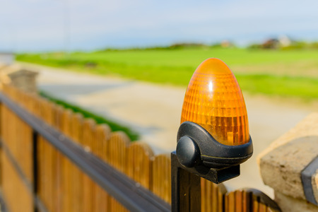 Automatic gate - wooden gate with warning lamp detail - close upの写真素材