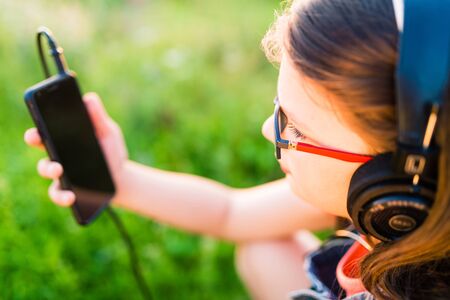 Teen girl listening to music with her retro vintage headphones outdoor