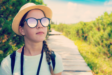 Hiking teenage tourist girl in sunglasses in the mountains - vintage toned imageの写真素材