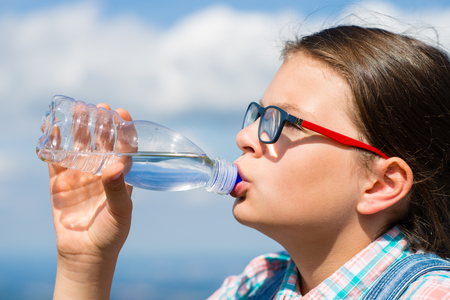 Young girl drinking water outdoorsの写真素材