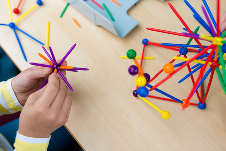Two little girls playing with lots of colorful plastic sticks kit indoors. kids having fun with building  geometric figures and learning mathematics in preschool or primary class of schoolの写真素材