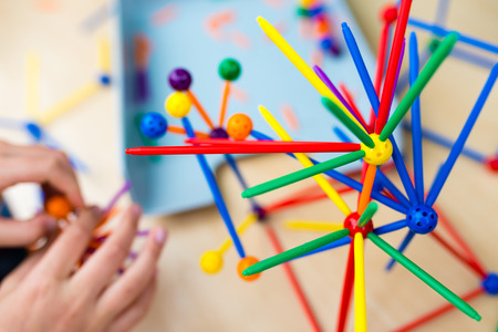 Two little girls playing with lots of colorful plastic sticks kit indoors. kids having fun with building  geometric figures and learning mathematics in preschool or primary class of schoolの写真素材