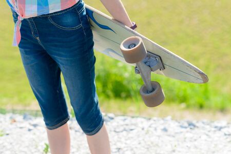 Young skateboard girl holding her longboard outdoors on sunset. Hipster girl with skateboardの写真素材