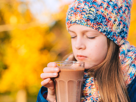Happy smiling young girl drinking chocolate milkの写真素材