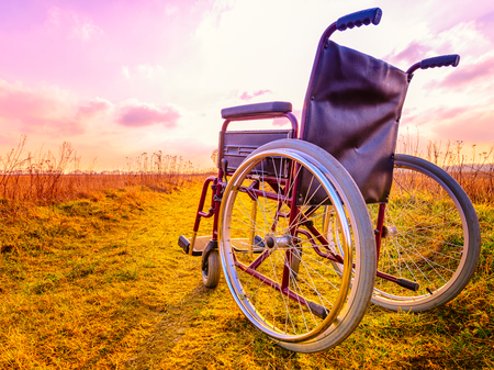 Empty wheelchair on the meadow at sunset. Miracle concept. Healed person raised and went awayの写真素材