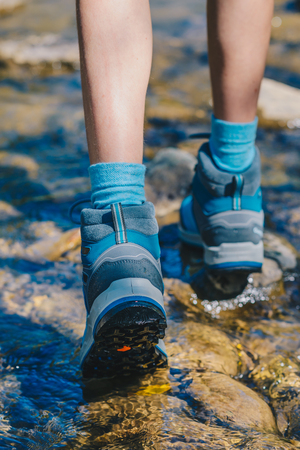 Hiking shoes - sole of trekking boots and legs in a mountain stream. Tourist trekking or walking sidewalk. Healthy outdoor fitness lifestyleの写真素材