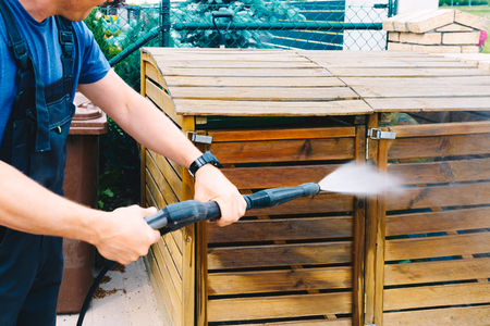 A man cleaning dirty wooden garden garbage with a high-pressure cleanerの写真素材