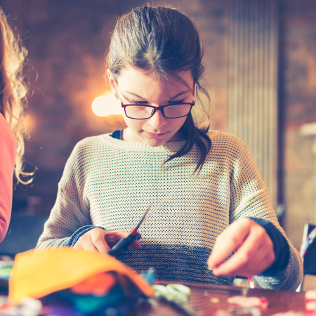tailor art workshops for children - a girl sewing felt decorations - colorful fabrics lying on a tableの写真素材