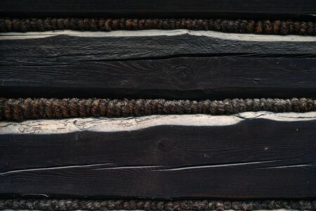 old black wooden wall of a barn - with boards and beams joined in a traditional way - wood towed