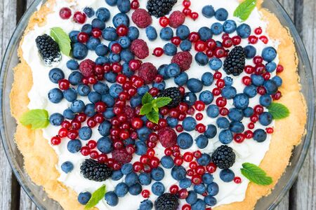 Tart with fresh blueberries, raspberries, blackberries, red currants and whipped cream decorated...
