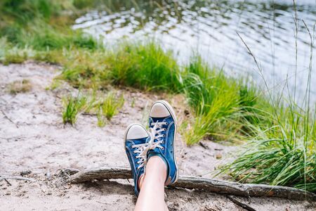 Foot and legs seen from above on a sandy lake beach. Selfie of sneakers on the ground great for any use.の写真素材