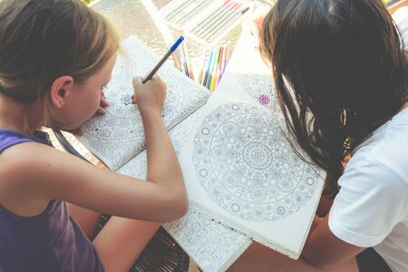 Little girls paint a coloring bookの写真素材