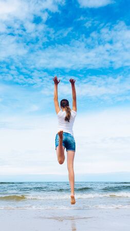 Happy girl jumping on the beach at day timeの写真素材