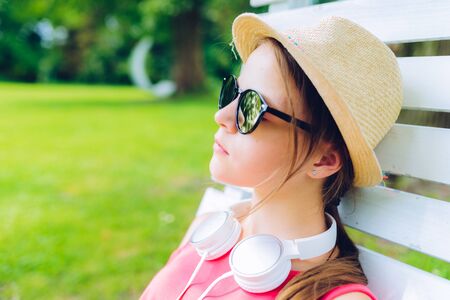 young girl resting on a hanging wooden chair in the gardenの写真素材