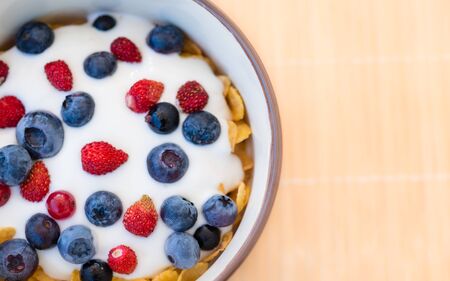 Healthy breakfast - Cornflakes with fresh blueberries, raspberries, wild strawberries and yogurt