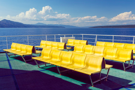 Empty yellow chairs - benches - on the upper deck of the Adriatic ferry in Croatia