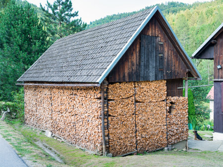 Huge woodshed in the mountains filled with pieces of chopped firewood - airy, with a storage room...