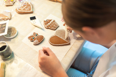 Culinary workshops for children and gingerbread decorating. Young girl decorating gingerbread cookies in the shape of a heartの写真素材