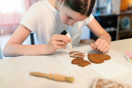 Girl decorating gingerbread cookies with icing sugar. Selective focus.の写真素材