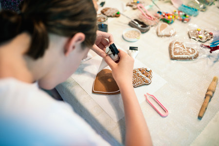 Girl decorating gingerbread cookies with icing sugar. Selective focus.の写真素材