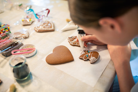 Close-up of a young girl decorating gingerbread cookies with icing.の写真素材