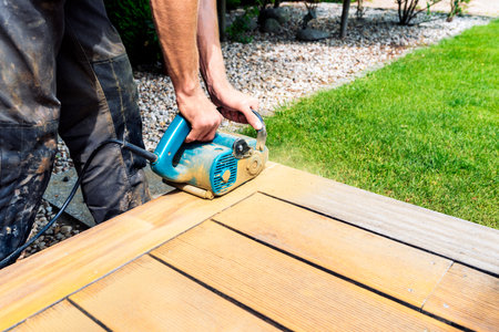 Machine cleaning of a wooden terrace - dry method - grinding the boards with handy sanding machine, preparing for oiling the terraceの写真素材