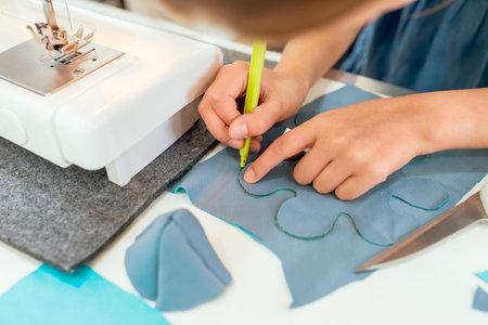 Close-up of a child's hands sewing on a sewing machine
