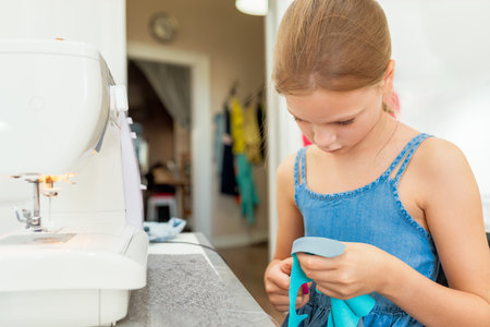 Close up of a young girl cutting a piece of fabric with scissors. Creative tailoring workshops for children - conceptの写真素材