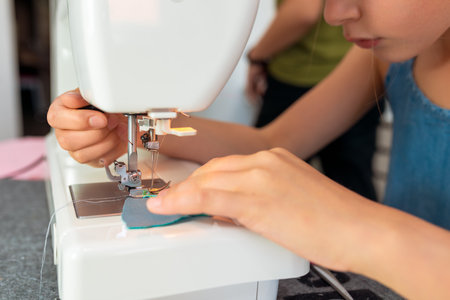 Little girl using a sewing machine to sew on a piece of fabric. Creative tailoring workshops for children - conceptの写真素材
