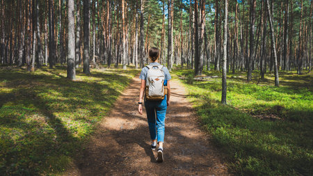 Young woman with backpack hiking in the forest. Hiking concept.