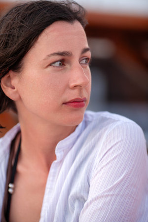 Close-up portrait of a thoughtful woman gazing into the distance in an outdoor settingの写真素材