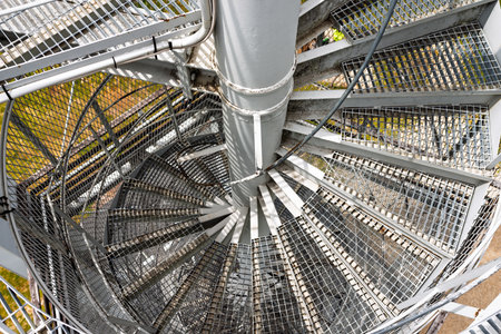 Top-down view of industrial metal spiral staircase with grated steps and central column forming...