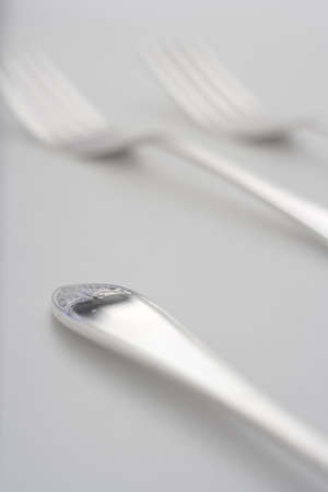 close-up of decorative silver end of cutlery and two fuzzy forks on the background