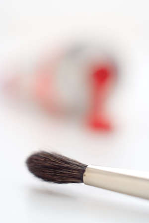 close-up of artistic brush tip with fuzzy paint tube on the background