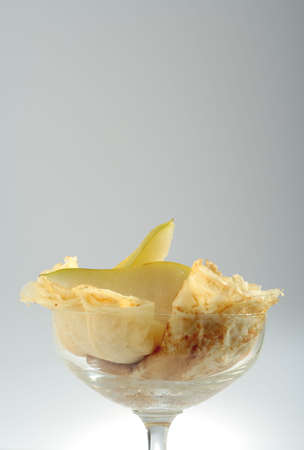 Close up view on dessert from folded pancakes and pears' pieces arranged in glass bowl. Photo with copy space at top.の写真素材