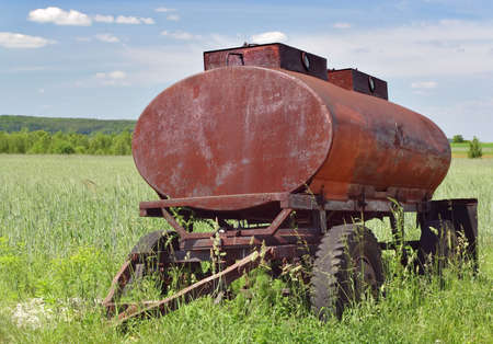 Abandoned old rusty water tanker on meadowの写真素材
