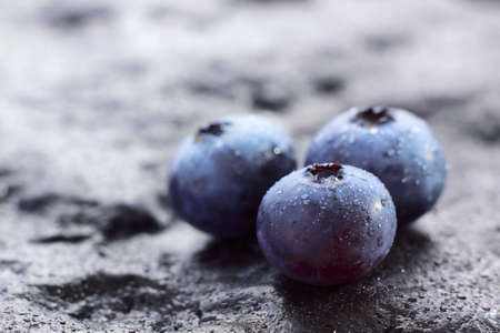 Blueberry (Northern Highbush Blueberry) fruits on dark painted stone with water drops