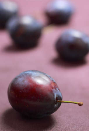 Plum on textile with unfocused plums on backgroundの写真素材