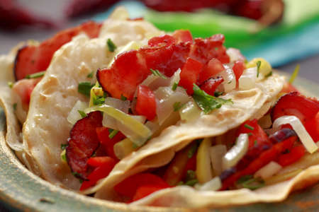 Close-up of wraps filled with fried bacon, chopped yellow bean pods, pepper, onion and parsleyの写真素材