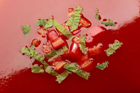 Close-up of cream tomato soup with chopped red pepper and green herbsの写真素材