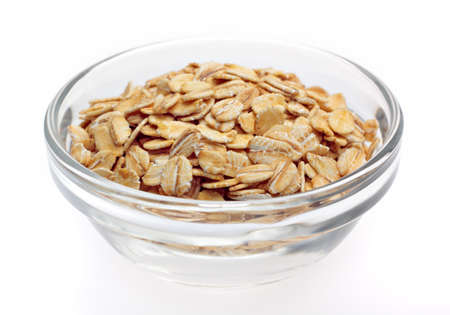 Wheat flakes in glass bowl on white background
