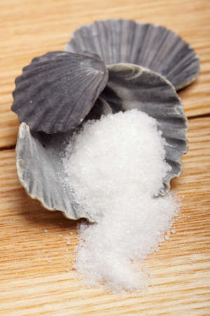 Sugar in dark scallop shell on natural wood board