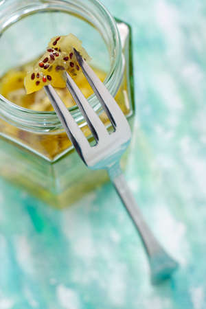 Kiwi fruit jam on fork over opened jar screw filled with jam. Shallow depth of field.の写真素材