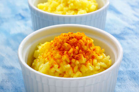 Ramekins filled by white long grain rice (boiled with curcuma) and curcuma powder toppingの写真素材