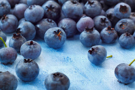 Blueberries lying on blue painted textile background