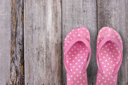 pair of pink slippers on plank woodの写真素材